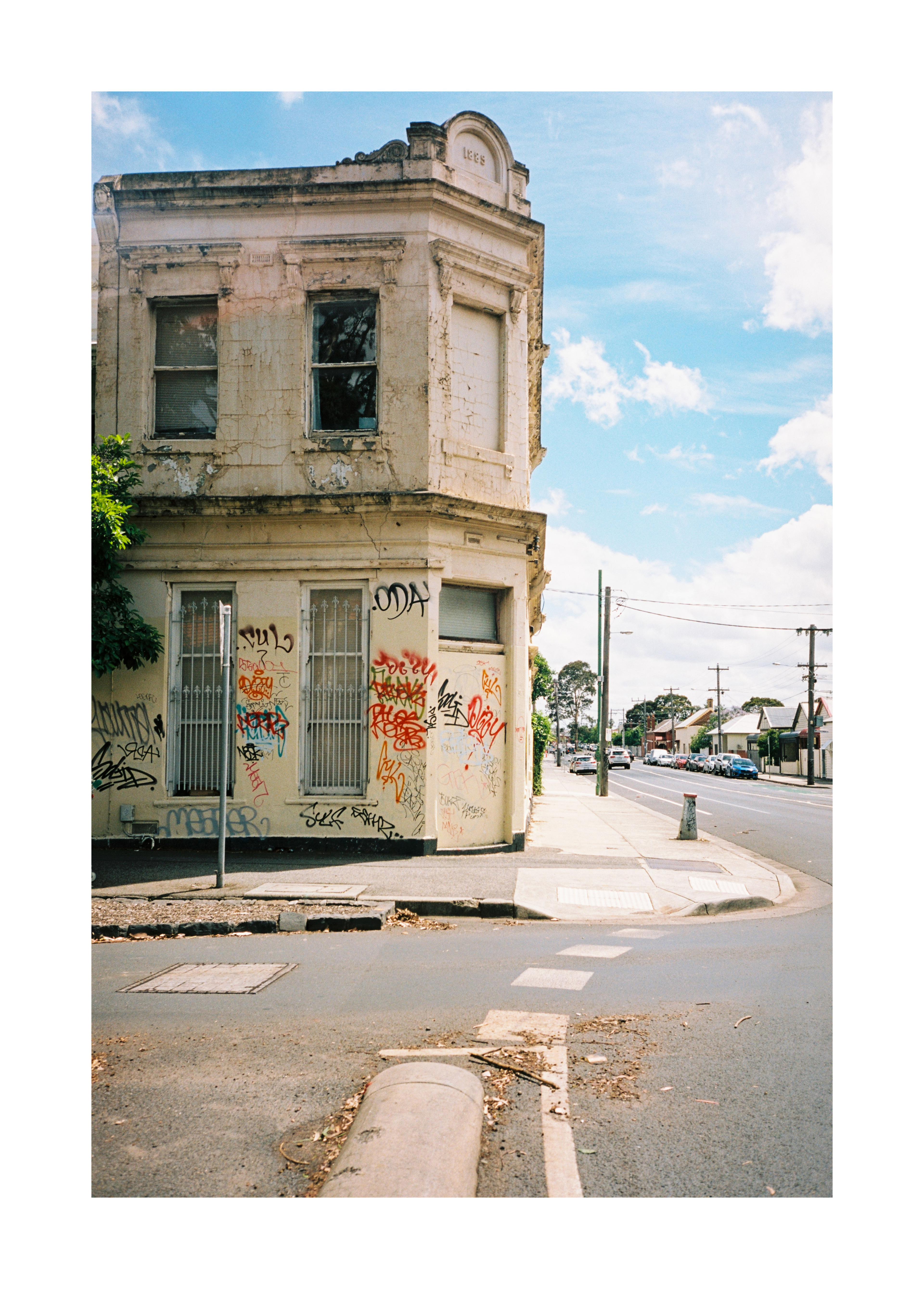 A graffiti-covered corner building on a quiet suburban street